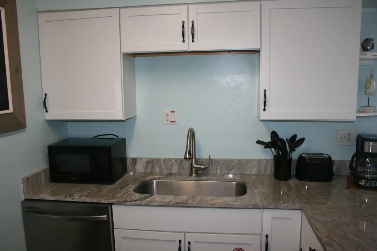 A close-up of the kitchen sink and surrounding countertop, with small appliances visible—likely a coffee maker or toaster—alongside space for meal prep. This angle gives a practical view of the amenities and emphasizes day-to-day convenience.
